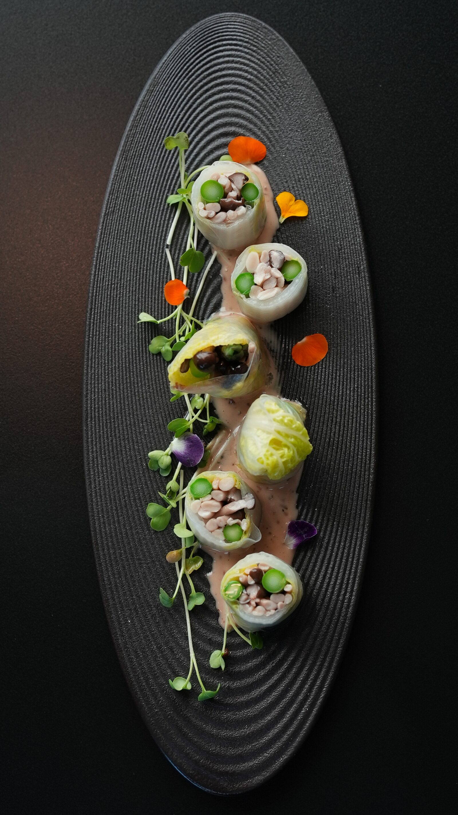 Colorful vegetable summer rolls on ribbed black plate